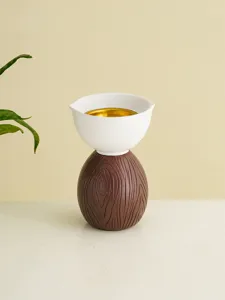 Vista detallada del quemador de incienso de cerámica creativo con base de madera y oro.