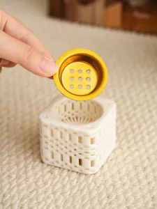 Ceramic 3D printed incense burner detail view showing the golden lid and white mesh base.