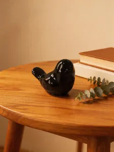 Close-up detail of a sleek black ceramic bird figurine on a wooden table, perfect decor.