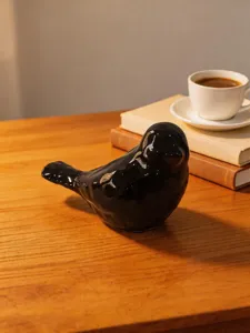 Minimalist black ceramic bird figurine detail, elegant desktop decoration for home office.