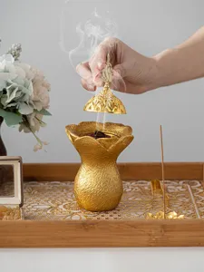 Gros plan d'un brûle-encens en résine lotus doré avec détail de fumée dans le décor de vie.