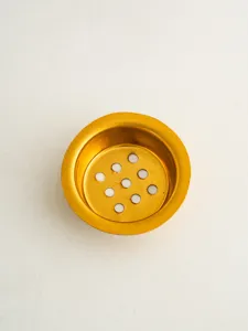 Detailed close-up view of the golden metal strainer component with precision perforated hole pattern.