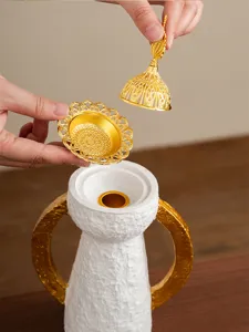 Incensiere arabo in stile tempio dorato con coperchio metallico e supporto bianco decorativo.
