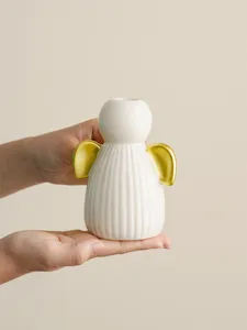 Gros plan détaillé du bougeoir ange en céramique moderne avec ses belles ailes dorées.