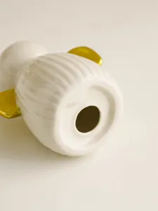Vue détaillée d'un bougeoir ange en céramique blanche avec ailes dorées, décoration intérieure.