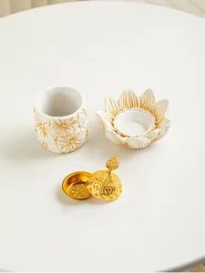 Detailed view of Arabic gold and white floral incense burner set components on white table.