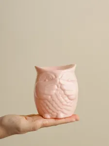 Close-up of pink ceramic owl candle holder and aroma burner detail, smooth glazed finish.