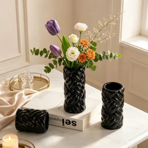 Modern minimalist black ceramic twisted vase for home decor, elegant cylindrical floral arrangement.