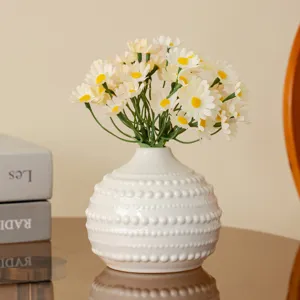 Détail de vase en céramique nordique, design texturé à pois blancs avec fleurs de marguerites.