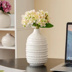 Gros plan d'un vase en céramique blanche perlé avec des hortensias artificiels décoration