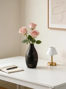 Modern ceramic vase with gold symbol details and pink roses on a clean desktop for home decor.