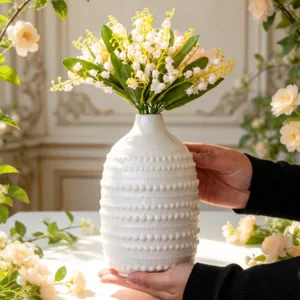 Vase en céramique blanche nordique avec muguet artificiel, élégant décor de table.