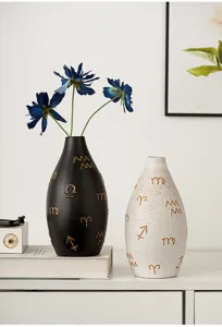 Detail view of modern ceramic vases with gold embossed symbols in a home setting.