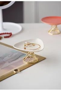 Detail shot of a modern ceramic jewelry tray with gold metal stand for desktop decor.