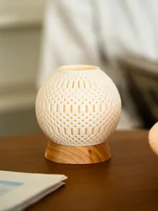 Close-up detail view of spherical hollow 3D printed candle holder with natural wooden base.