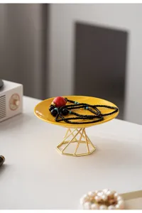 Detail shot of modern ceramic jewelry tray with gold metal stand for elegant desktop storage.