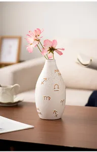 Ceramic vase with golden zodiac symbols for stylish desktop floral arrangement and home decor.