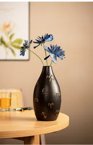 Modern black ceramic vase with gold zodiac symbols and blue flowers for home decor and desktop.