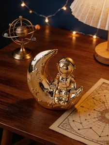 Detailed view of modern creative gold astronaut and moon ceramic ornament for home desktop decor.