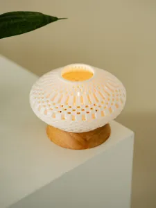 Ceramic hollow candle holder detail, white 3D printed mesh texture with wooden base.