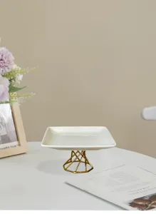 Detail view of modern minimalist white ceramic tray with gold metal stand for home decor.