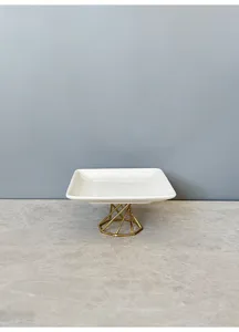 Ceramic jewelry tray with gold geometric metal stand, detail view of modern desktop storage.