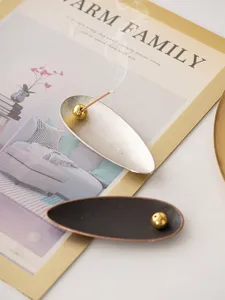Detailed view of creative metal willow leaf incense holder with a golden bead stick base.