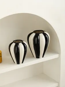 Minimalist black and white striped ceramic vase detail in modern home decor setting.