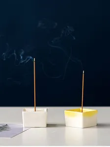 Close up detail of ceramic incense holder, minimalist square design with smoke effect.