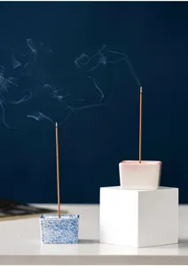 Ceramic incense burner detail, minimalist square design, elegant smoke and table display.