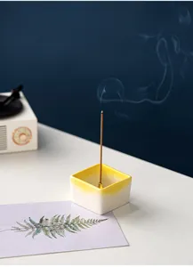 Ceramic square incense holder detail, yellow gradient rim, elegant tabletop scene display.