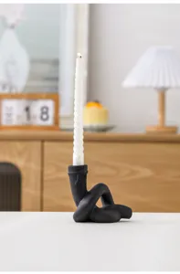 Gros plan du détail du bougeoir en céramique nouée noire moderne avec une bougie blanche.