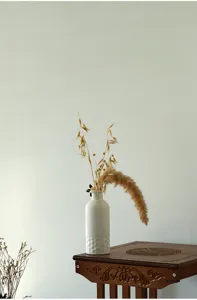 Vase en céramique blanche minimaliste nordique avec base texturée, détail de fleurs séchées.
