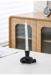Gros plan sur le porte-bougie en céramique noire avec bougie spirale blanche sur la table.