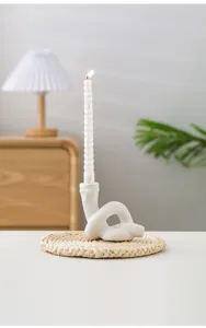 Vue détaillée du bougeoir en céramique nouée créatif avec bougie torsadée sur natte.