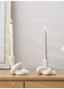 Gros plan d'un bougeoir en céramique en forme de nœud créatif avec bougies pour la déco.