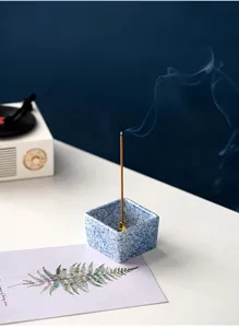 Detailed view of a minimalist square ceramic incense stick holder with blue speckled glaze and brass insert.