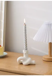 Bougeoir en ceramique en forme de noeud creatif avec bougie torsadee pour la maison.