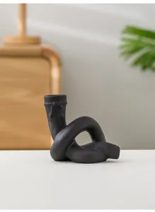 Gros plan du bougeoir en céramique noire avec détail de nœud et texture pour déco de table.