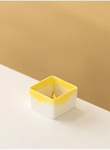 Minimalist square ceramic incense holder detail with gradient yellow and white tone decor.