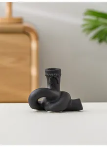 Détail bougeoir en céramique noire nœud, design artistique créatif pour décoration de table.