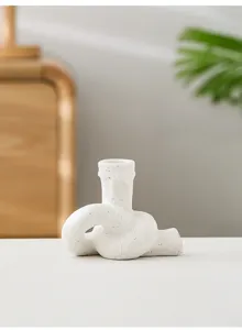 Vue détaillée du bougeoir en céramique blanche en forme de nœud, déco de table artistique et moderne.