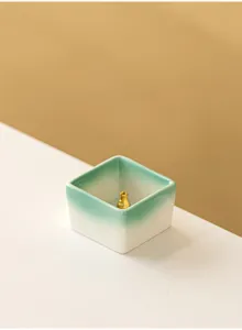 Detailed close-up of a minimalist square ceramic incense burner with gradient green and white.