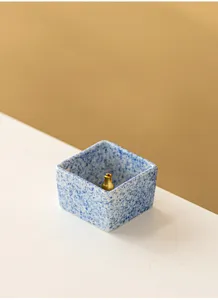 Minimalist square ceramic incense holder with blue speckles and gold brass stick base detail view.