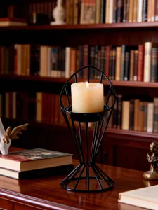 Modern minimalist black metal wire candle holder detail shot with lit pillar candle on desk