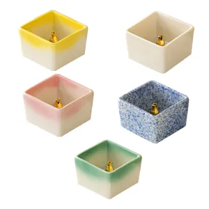 Close-up details of square ceramic incense stick holders featuring various gradient colors and brass pins.