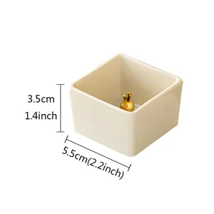Detail view of a minimalist square ceramic incense holder with golden pin, compact size.