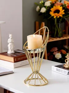 Detail shot of modern gold geometric metal candle holder with white pillar candle interior.