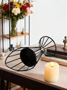 Close-up detail of the modern minimalist black metal geometric candle holder on wooden table.