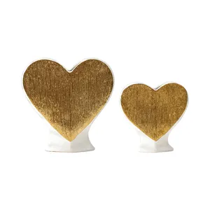 Set of two elegant ceramic heart vases in white and gold finish for modern home decor display.
